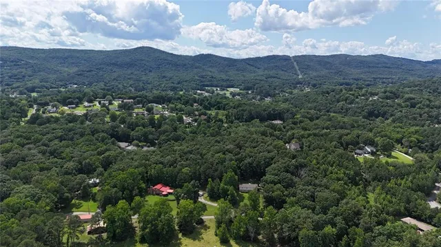 an empty room with wooden floor and windows with curtains