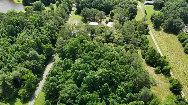 an aerial view of residential house with outdoor space and trees all around