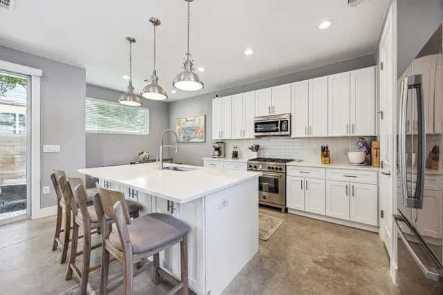 a kitchen with a stove a sink a kitchen island with a dining table and chairs
