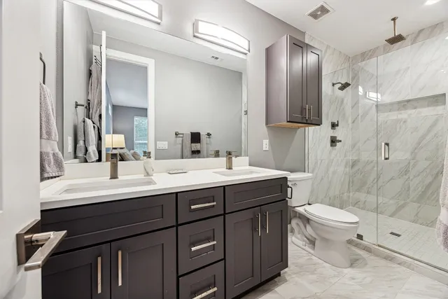 a bathroom with a double vanity sink toilet and shower