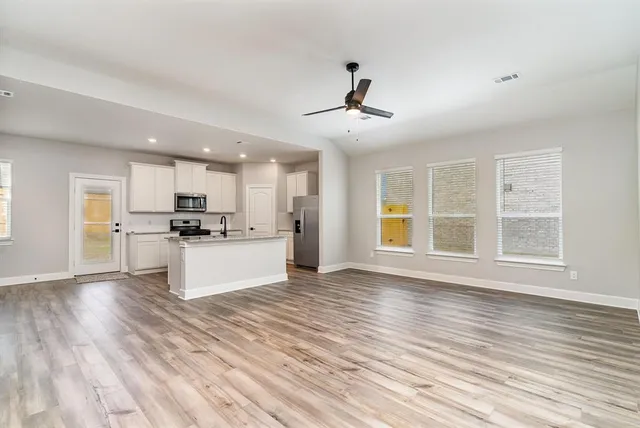 a view of an empty room with window and wooden floor