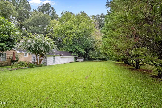 a view of a large trees with barn in the background