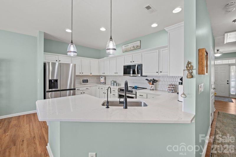 16515 Amberside Road East Cornelius, NC 28031 - Photo 13 of 35 a kitchen with stainless steel appliances a sink a stove a refrigerator cabinets and wooden floor