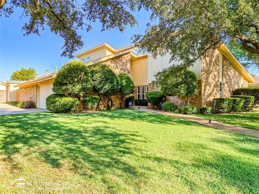 Mid-century home with a front lawn, stucco siding, an attached garage, and brick siding