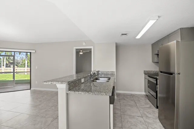 an empty room with sliding glass door and chandelier fan