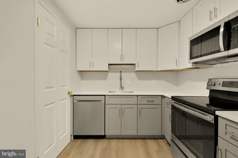 a kitchen with stainless steel appliances granite countertop white cabinets a sink and dishwasher