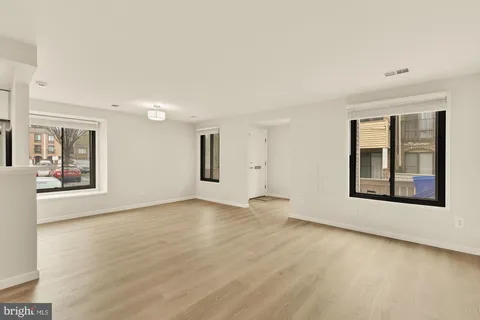 a view of an empty room with a window and wooden floor
