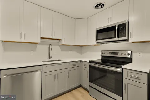 a kitchen with white cabinets and stainless steel appliances