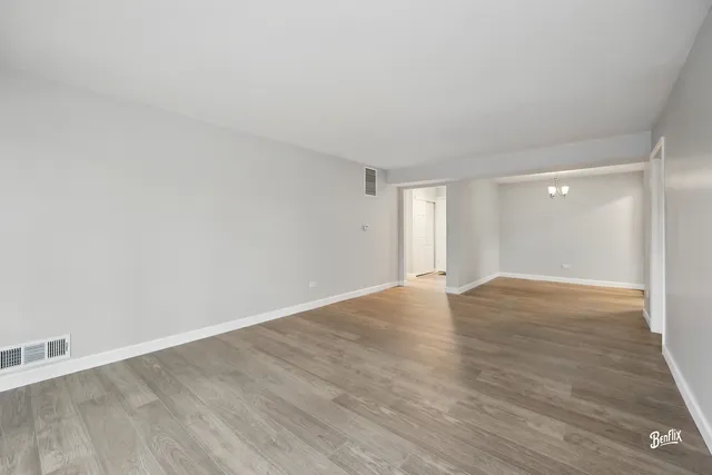 an empty room with wooden floor and chandelier