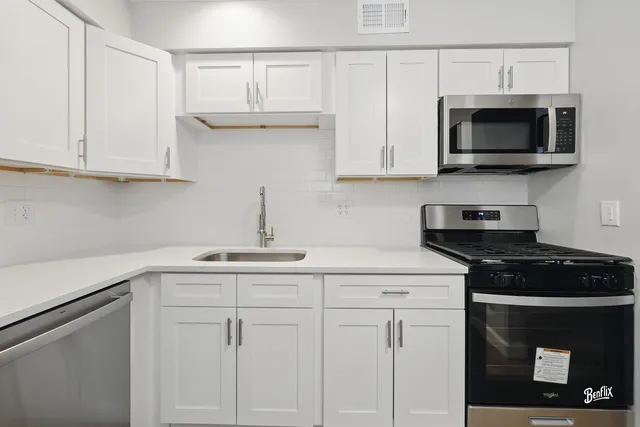 a kitchen with white cabinets and black appliances