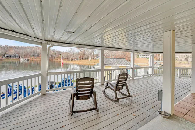 a view of a white house with a large tree and wooden fence