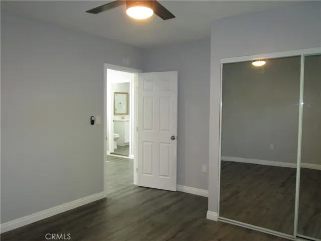 an empty room with wooden floor closet and windows