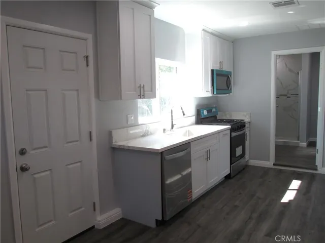 a view of cabinets a sink and dishwasher with wooden floor