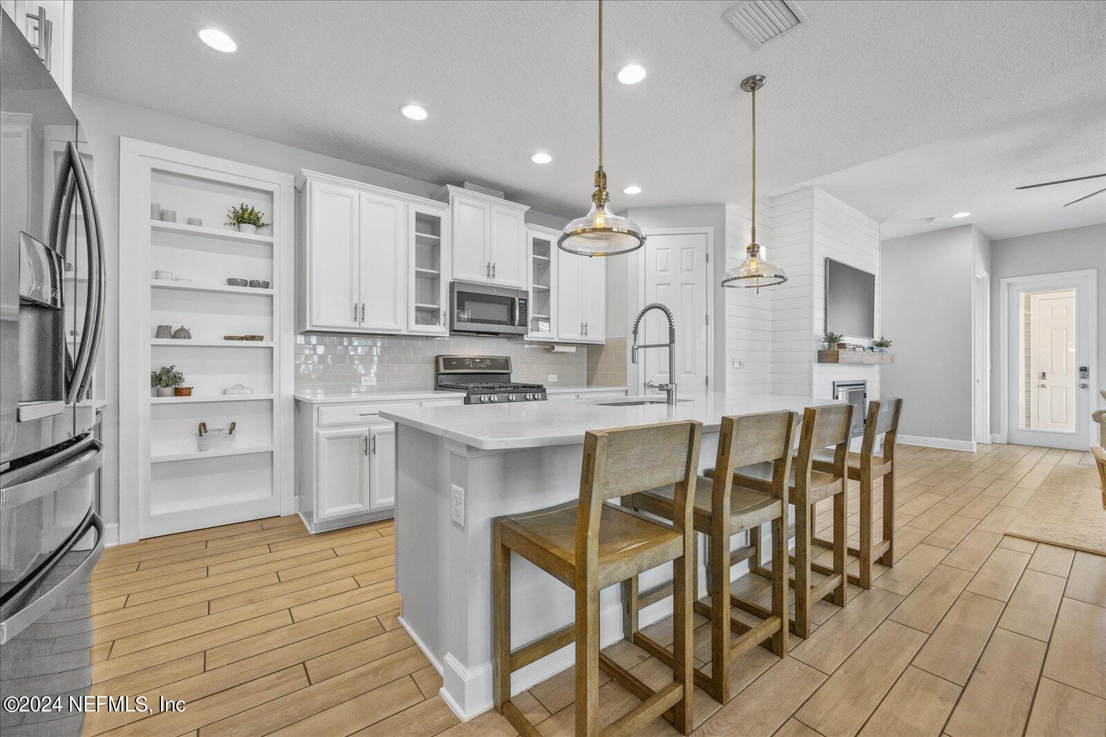 36 Foster Lane Ponte Vedra, FL 32081 - Photo 15 of 59 a kitchen with kitchen island granite countertop a table chairs microwave and cabinets
