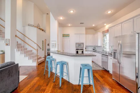 a kitchen with stainless steel appliances granite countertop a refrigerator a stove top oven and a dining table with wooden floor