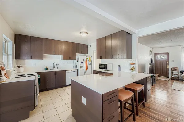 a kitchen with a refrigerator a stove a sink a dining table and chairs