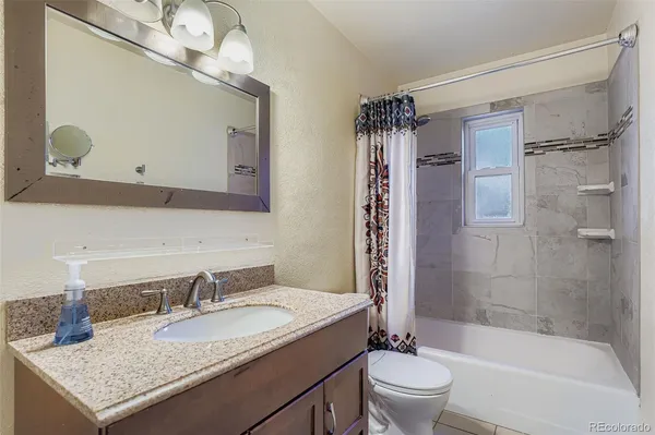 a bathroom with a granite countertop sink toilet and shower