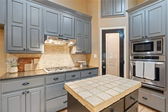 a kitchen with kitchen island granite countertop a stove refrigerator and microwave