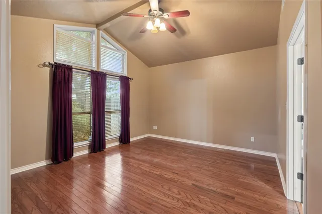 a view of an empty room with window and wooden floor