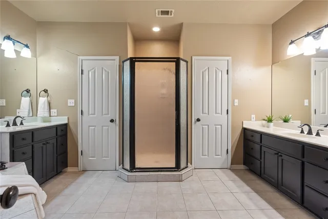 a spacious bathroom with a double vanity sink a mirror and a shower