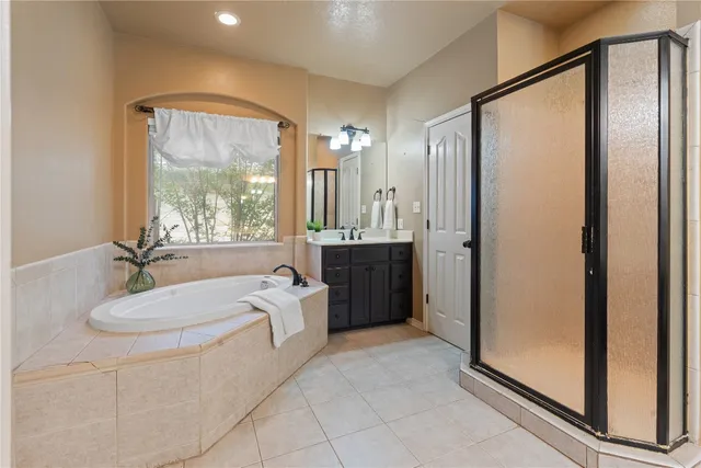 a spacious bathroom with a double vanity sink a mirror a bathtub and shower