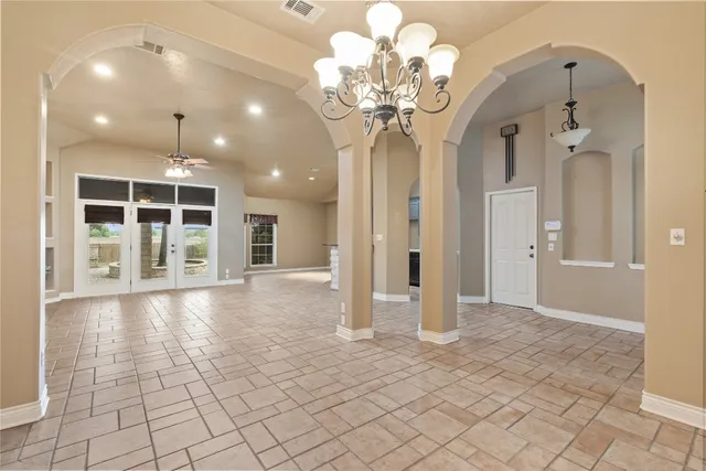 an empty room with kitchen view and windows