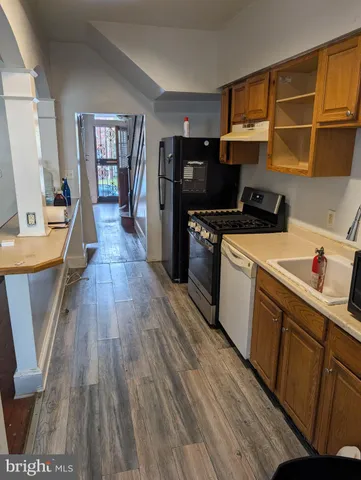 a kitchen with a wooden floor and a view of living room