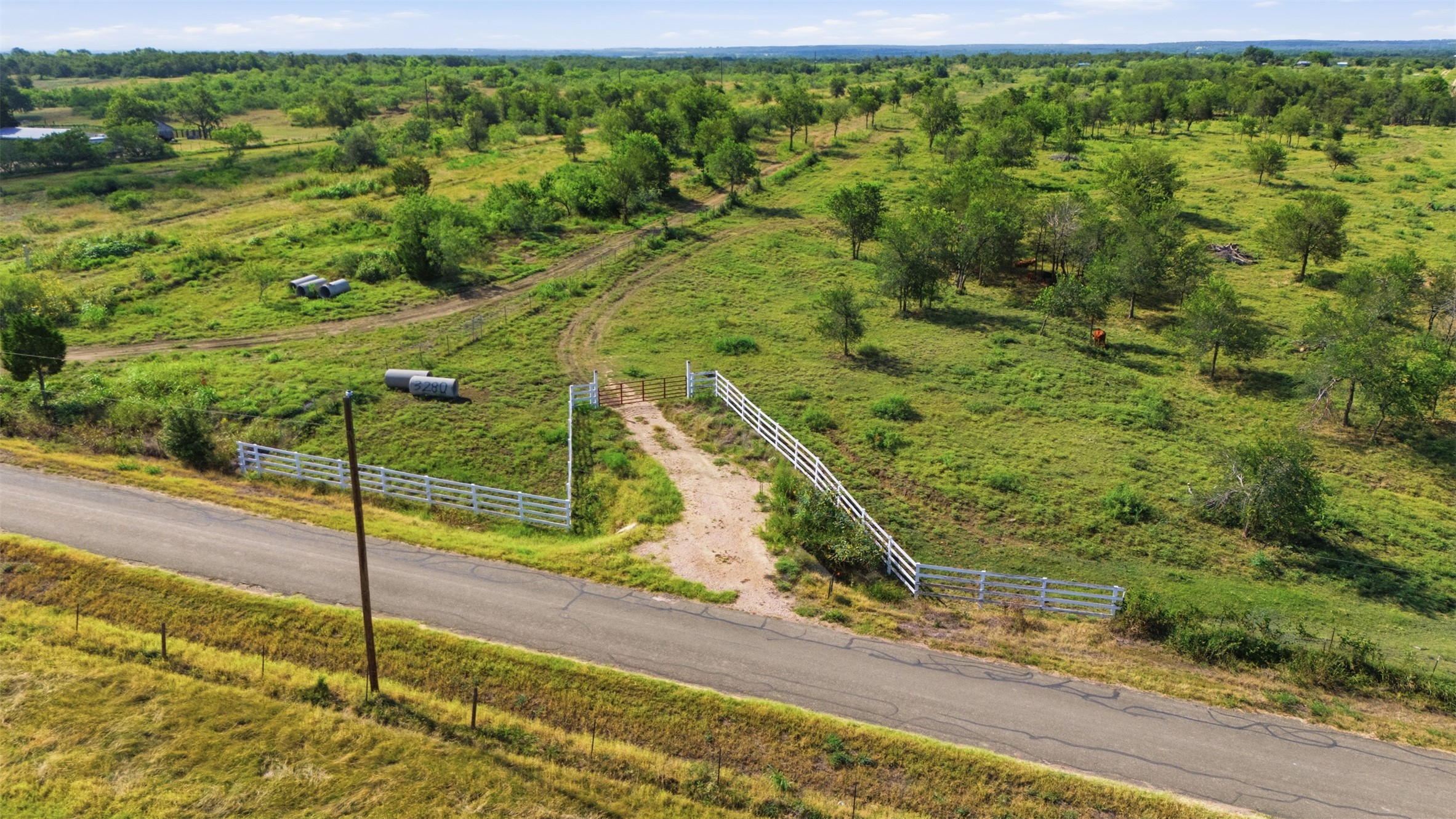3280 County Road 466 Elgin, TX 78621 - Photo 11 of 13 A rural property with verdant fields and scattered trees, offering vast open spaces and a private, gated entrance.