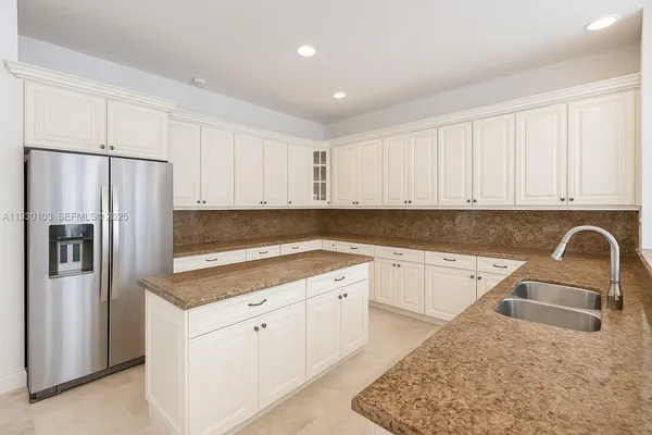 a kitchen with stainless steel appliances granite countertop a refrigerator a sink a stove with white cabinets
