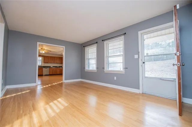 a view of an empty room with a window and wooden floor