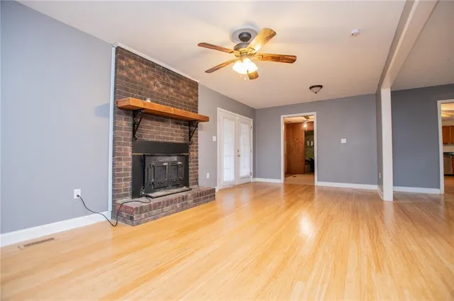 a view of an empty room with wooden floor and a fireplace