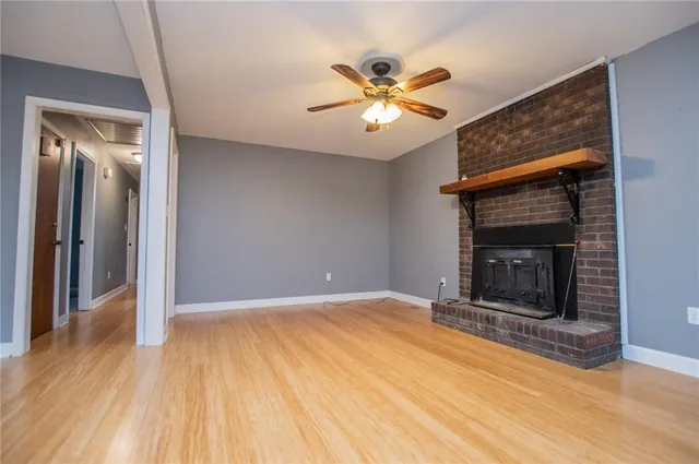 a view of an empty room with wooden floor and a fireplace