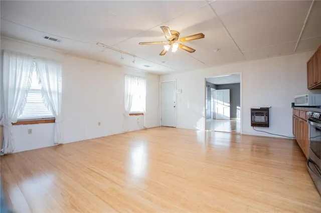 a view of an empty room with window and wooden floor