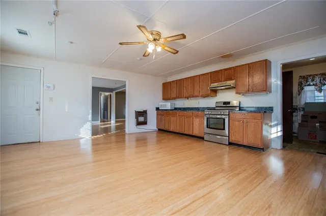 a living room with stainless steel appliances kitchen island granite countertop a stove and a wooden floors