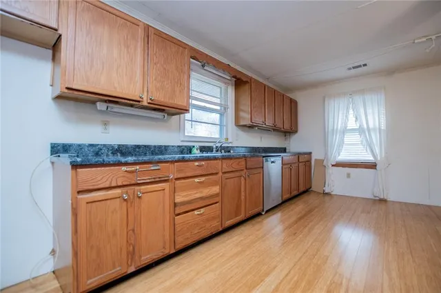 a kitchen with granite countertop wooden floors cabinets a sink and a window