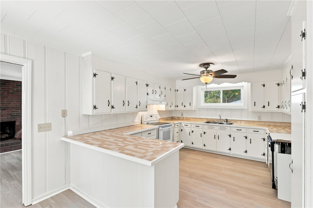 205 Timms Road Piedmont, SC 29673 - Photo 9 of 36 White cabinetry, tile countertops, and wood-style flooring define this functional u-shaped workspace.