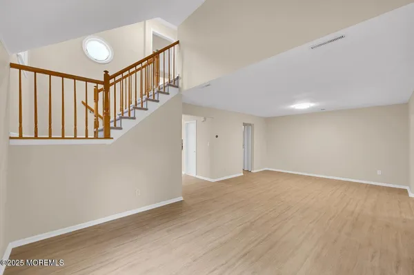 a view of an empty room with wooden floor and stairs
