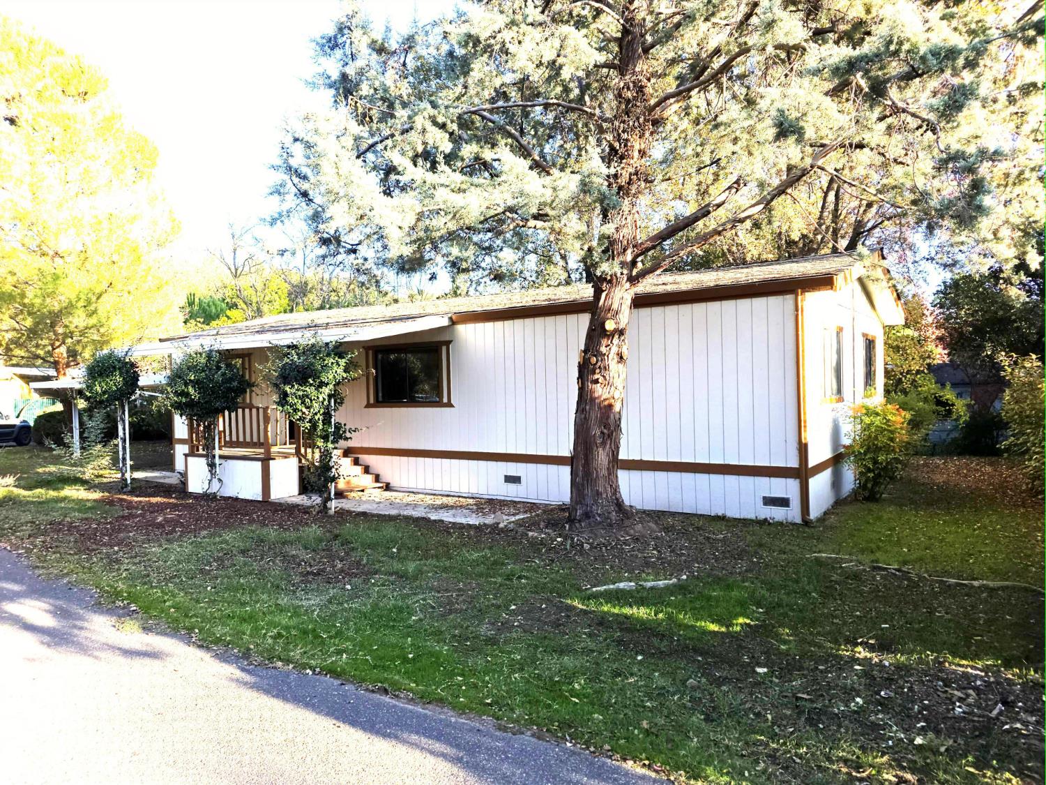 18330 Wards Ferry Road, Unit 59 Sonora, CA 95370 - Photo 2 of 10 a view of a white house with a big yard and large tree