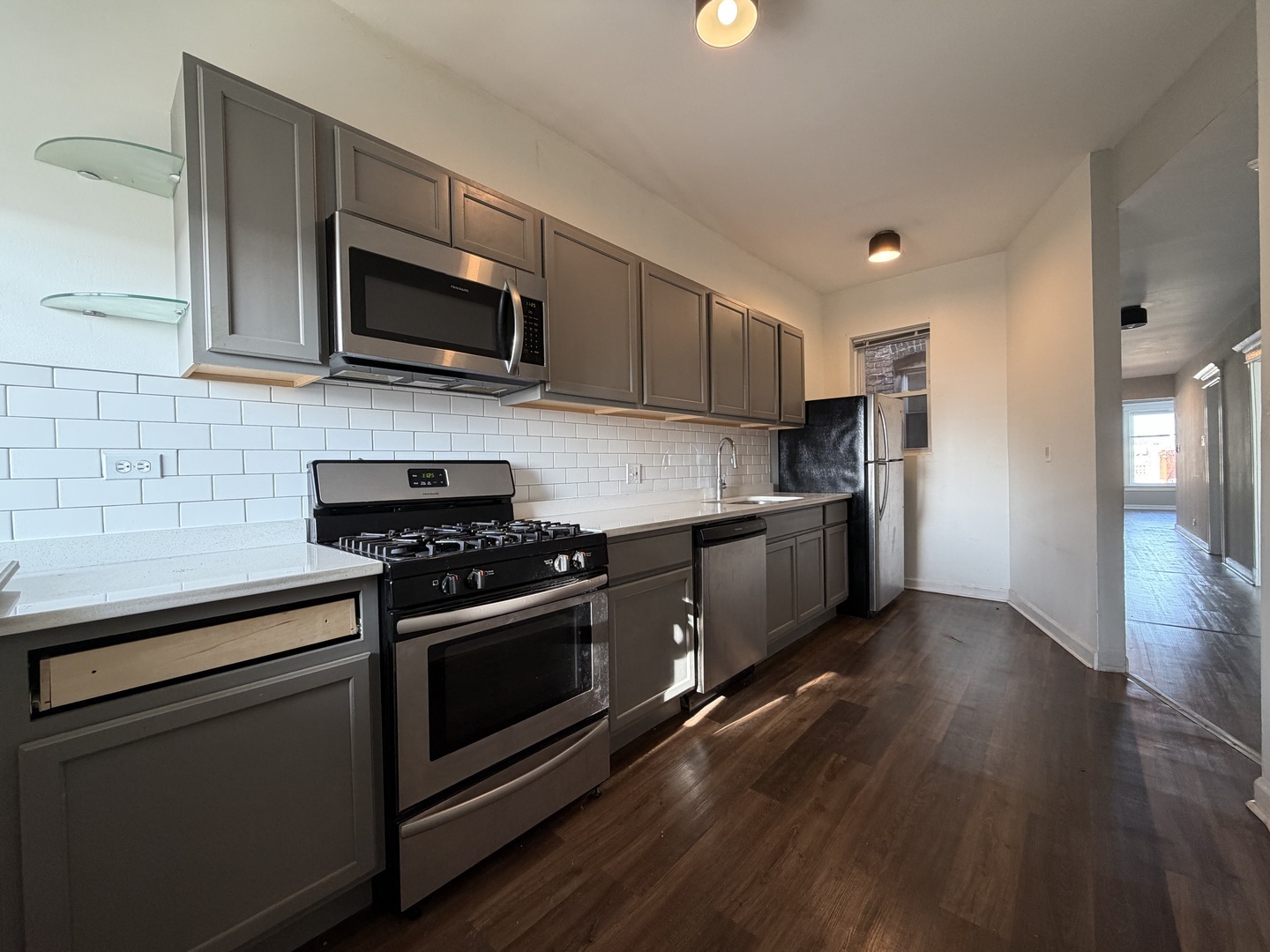 3339 West Adams Street, Unit 3E Chicago, IL 60624 - Photo 2 of 9 a kitchen with stainless steel appliances a sink dishwasher a stove and microwave with wooden floor