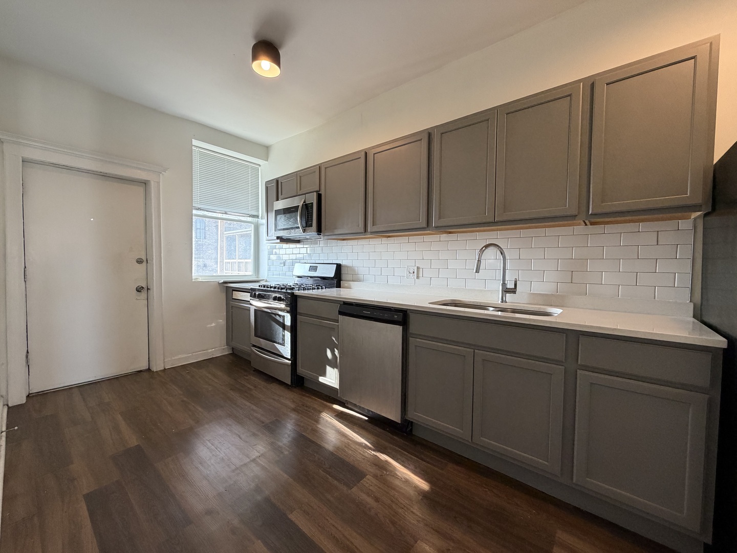 3339 West Adams Street, Unit 3E Chicago, IL 60624 - Photo 3 of 9 a kitchen with kitchen island granite countertop a sink cabinets and wooden floor