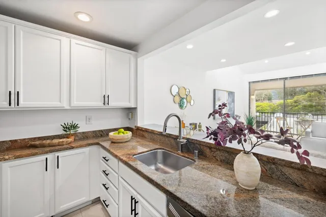 a kitchen with granite countertop a sink a stove and cabinets