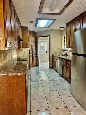 a kitchen with granite countertop a refrigerator and a stove top oven