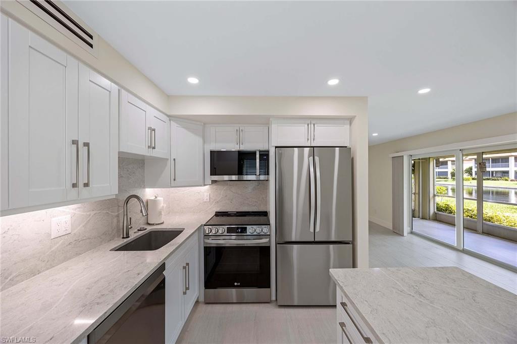 1155 Sandpiper Street, Unit F7 Naples, FL 34102 - Photo 1 of 29 a kitchen with a refrigerator a sink and a stove top oven