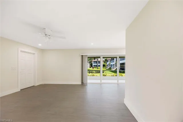 an empty room with windows and ceiling fan