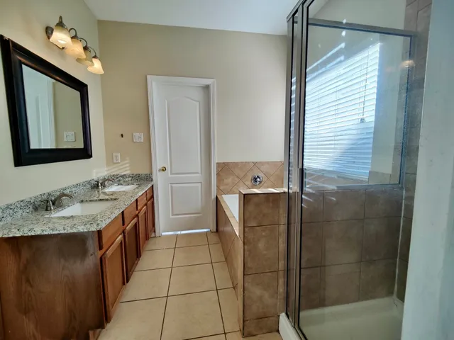 a bathroom with a granite countertop sink a mirror and shower