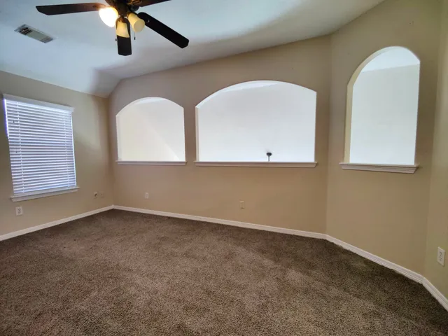 an empty room with windows and fan