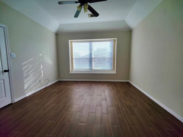 an empty room with wooden floor cabinet and windows