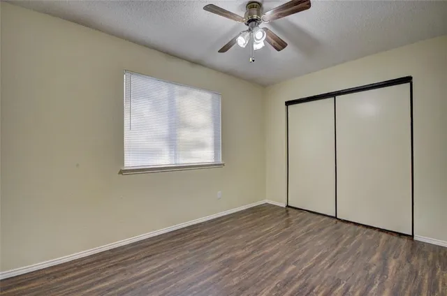 an empty room with wooden floor fan and windows