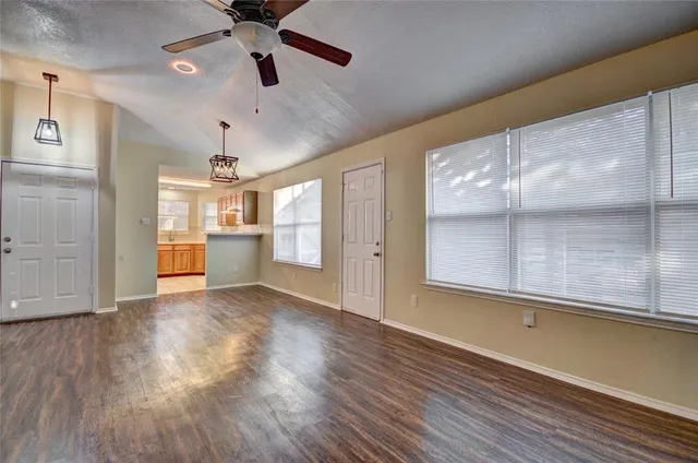 a view of an empty room with a window and wooden floor