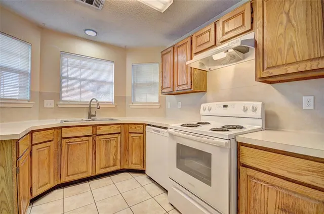a kitchen with cabinets appliances a sink and a window